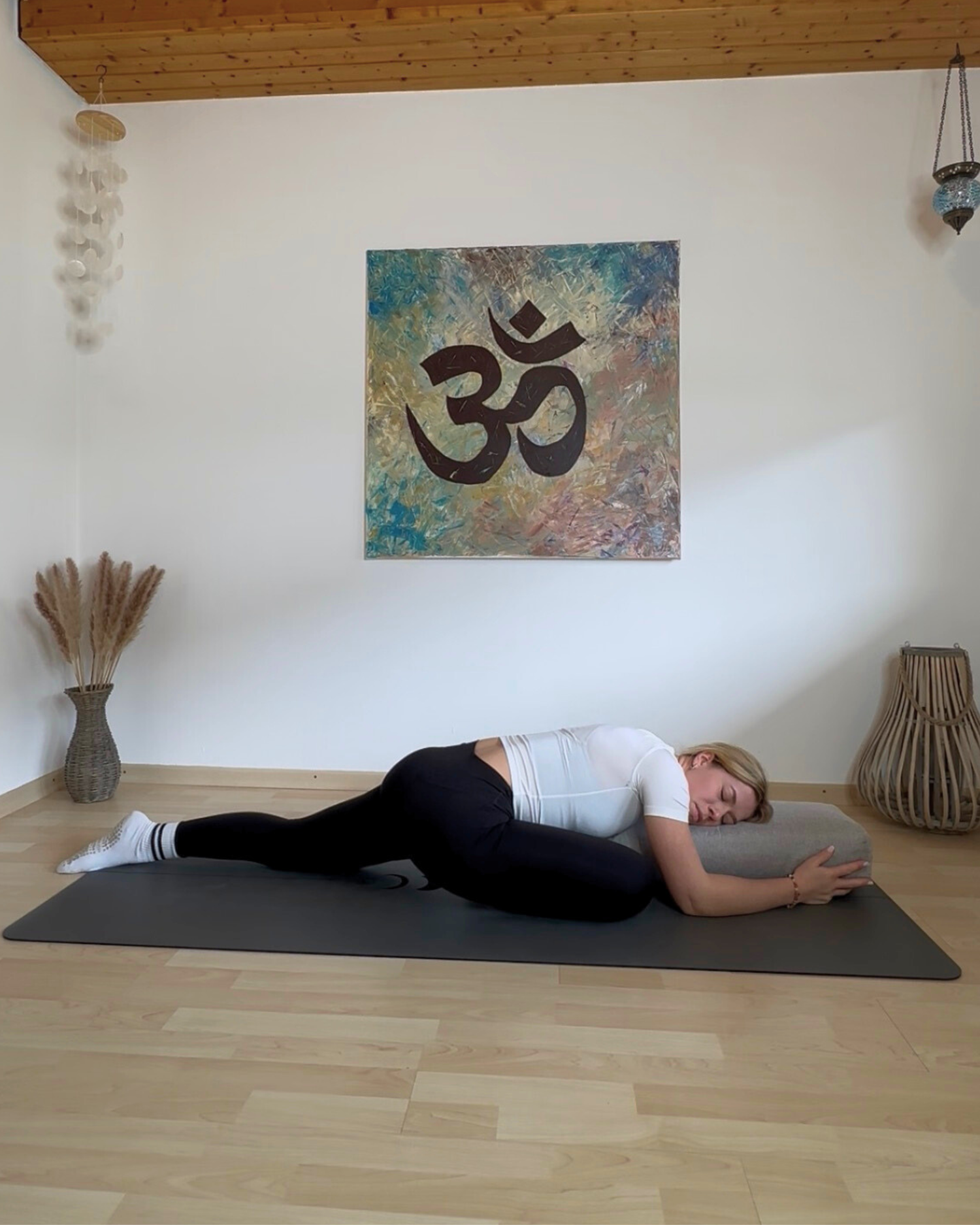 Frau ruht seitlich mit Oberkörper und Kopf auf dem Yoga-Bolster